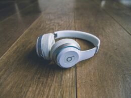 Weiße kabellose Beats by Dr. Dre Kopfhörer liegen auf einem schlichten Untergrund, Nahaufnahme der modernen Kopfhörer