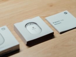 Weiße kabellose Computermaus in geöffneter Verpackung mit sichtbarer Gebrauchsanleitung auf einem Tisch