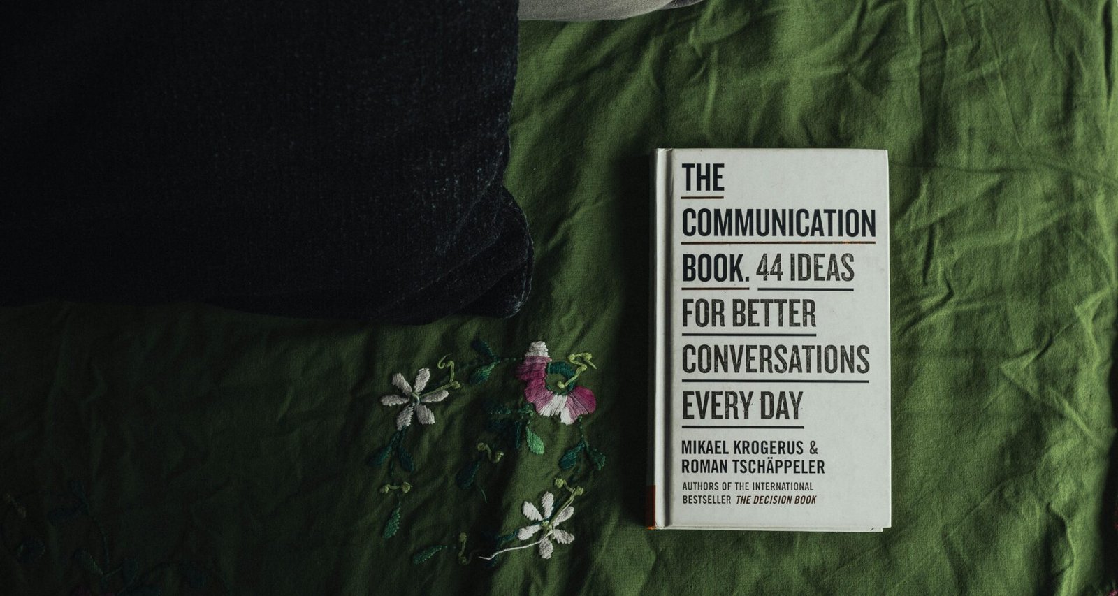 Zwei schlichte schwarze und weiße Boxen auf grün-weiß gemustertem Flachgewebe mit floralem Design