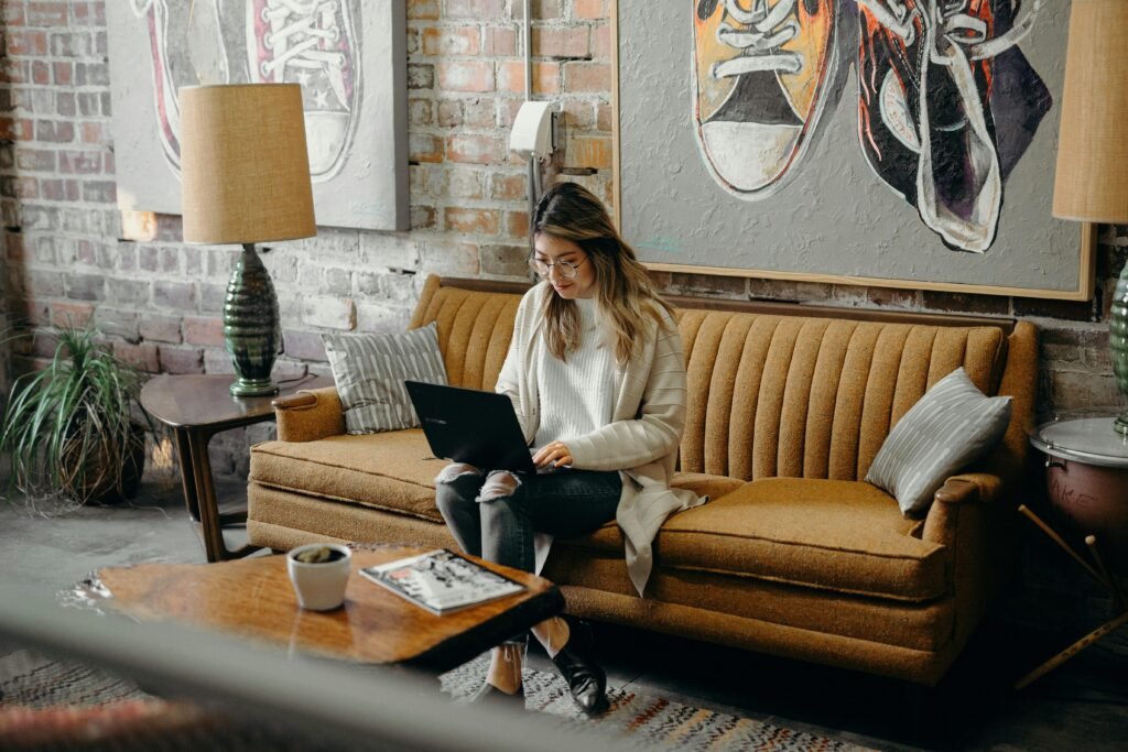 Frau sitzt auf einem Stuhl und arbeitet am Laptop, typische Szene im digitalen Arbeitsplatz oder Homeoffice.
