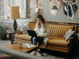 Frau sitzt auf einem Stuhl und nutzt einen Laptop für digitale Arbeit in einem modernen Innenraum
