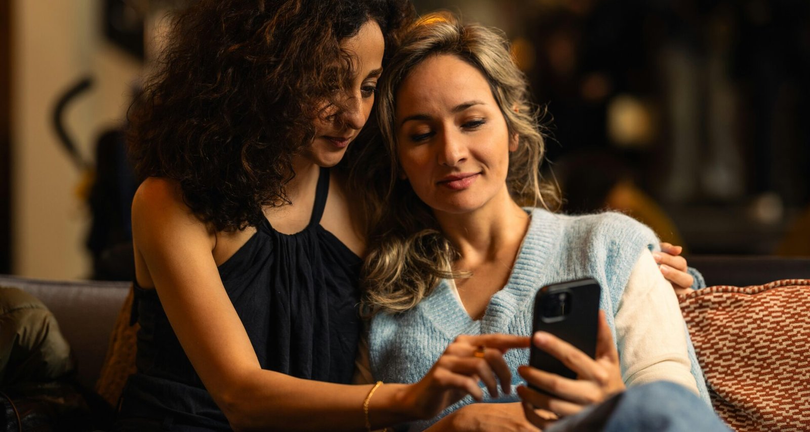 Zwei Frauen sehen gemeinsam auf ein Smartphone-Display und tauschen sich über digitale Inhalte aus