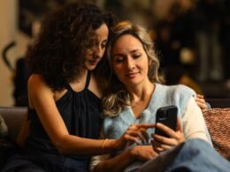 Zwei Frauen sehen gemeinsam auf ein Smartphone-Display und tauschen sich über digitale Inhalte aus