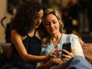 Zwei Frauen sehen gemeinsam auf ein Smartphone-Display und tauschen sich über digitale Inhalte aus