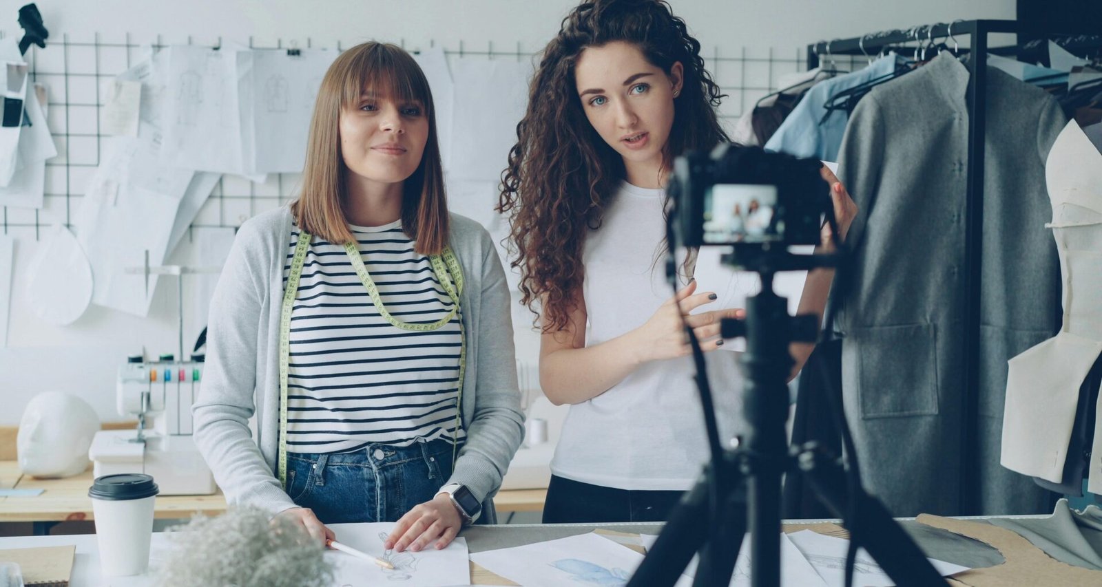 Zwei Frauen filmen gemeinsam ein Video zum Thema Mode mit professioneller Ausrüstung in einem modernen Raum.