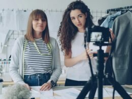 Zwei Frauen filmen gemeinsam ein Video zum Thema Mode mit professioneller Ausrüstung in einem modernen Raum.