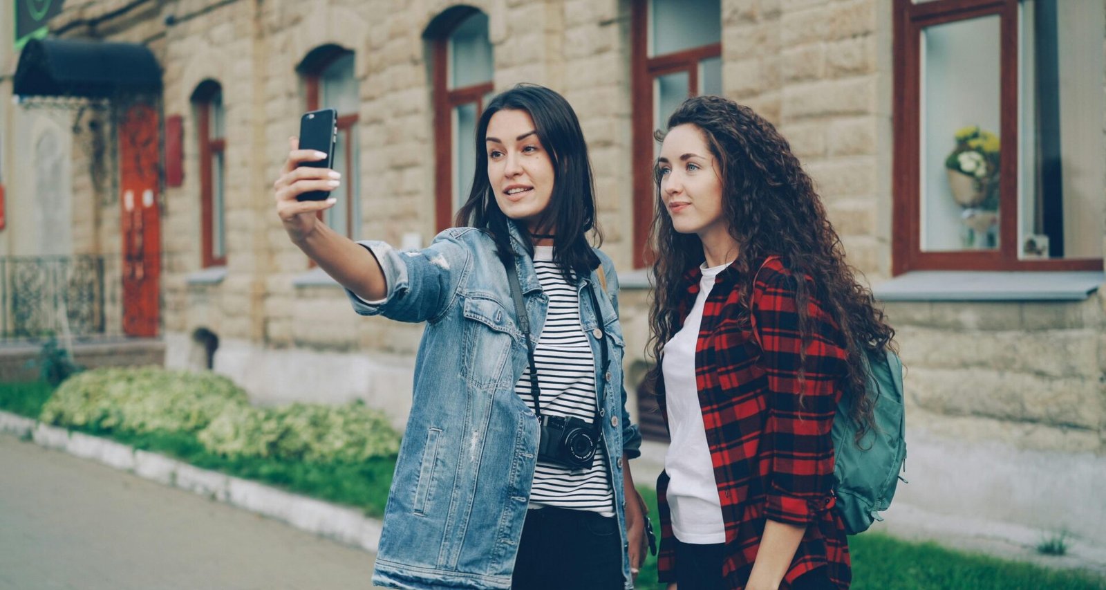 Zwei Freunde stehen auf einer Straße und machen zusammen ein Selfie mit dem Smartphone im städtischen Umfeld