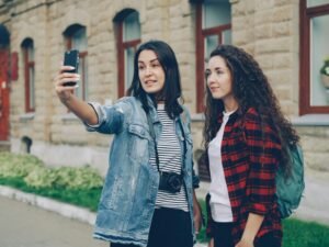 Zwei Freunde stehen auf einer Straße und machen zusammen ein Selfie mit dem Smartphone im städtischen Umfeld