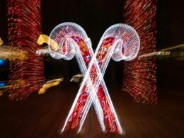 Zwei leuchtende Zuckerstangen mit roten Lichtern vor dunklem Hintergrund, fotografiert von Mick Haupt