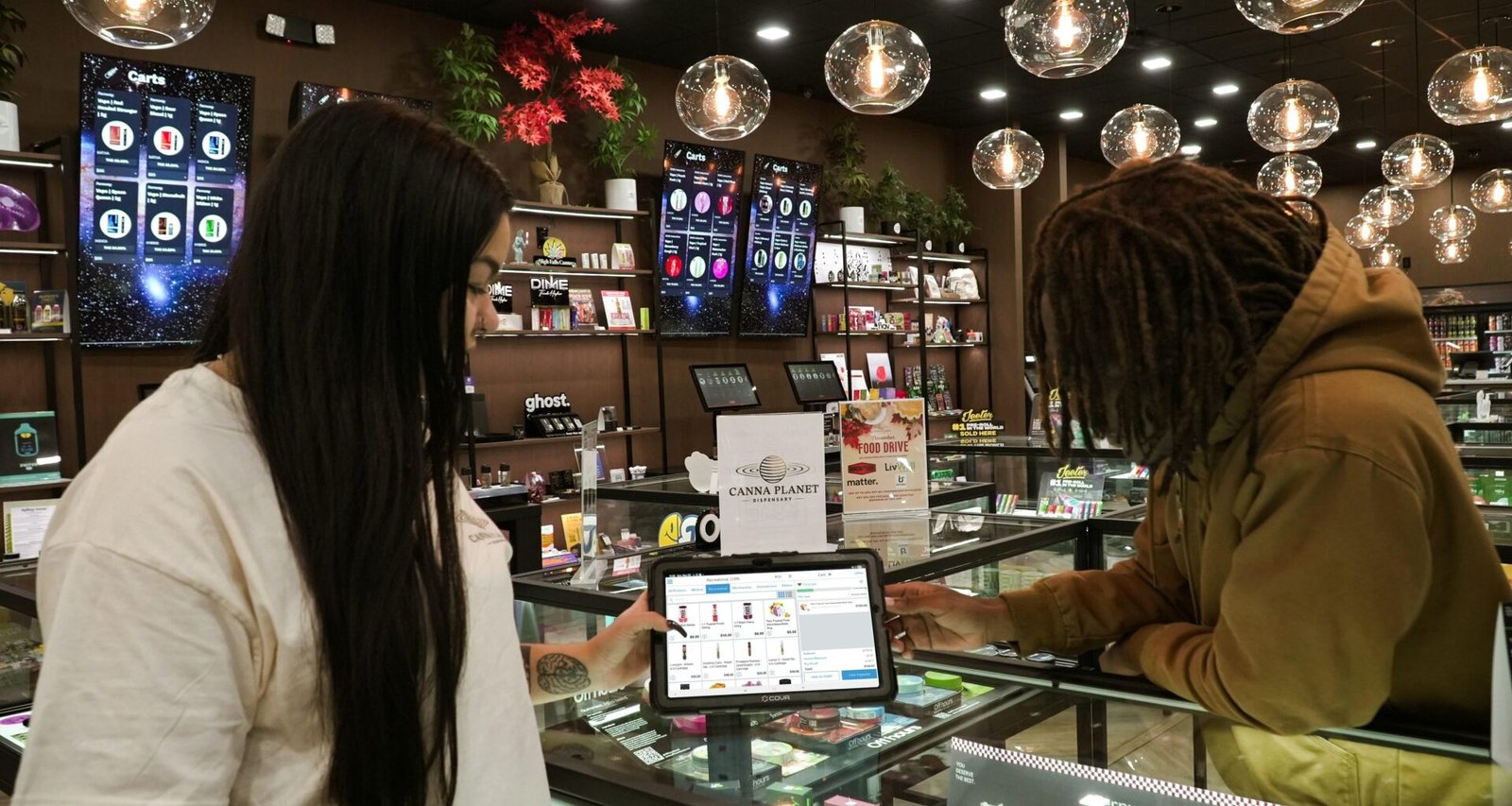 Zwei Menschen stehen an einem Tresen und bedienen gemeinsam ein Tablet, moderne digitale Arbeitsumgebung.