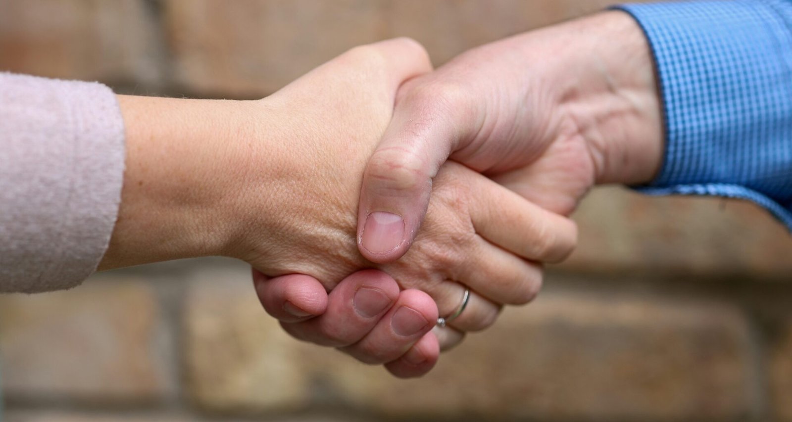 Zwei Menschen stehen sich gegenüber und geben sich zum Abschluss eines Gesprächs die Hand