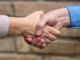 Zwei Menschen stehen sich gegenüber und geben sich zum Abschluss eines Gesprächs die Hand