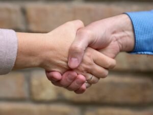 Zwei Menschen stehen sich gegenüber und geben sich zum Abschluss eines Gesprächs die Hand